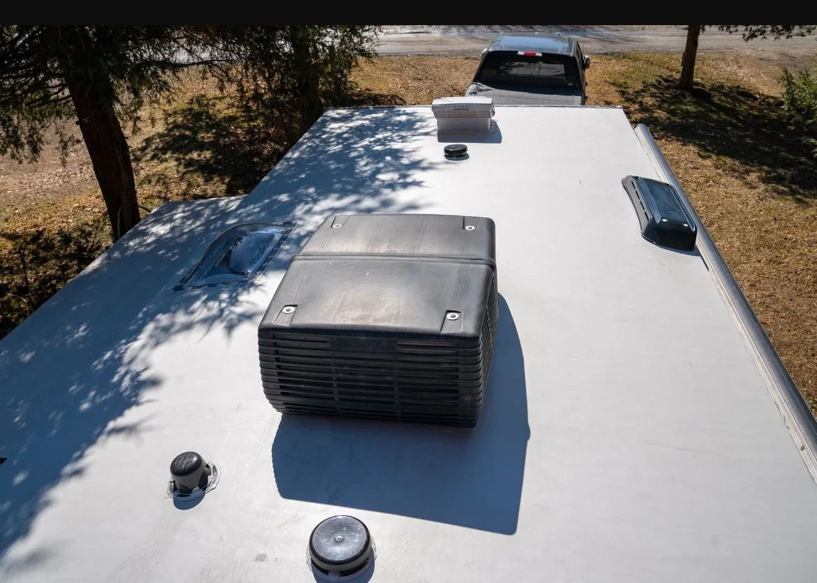 Technician inspecting an RV rooftop AC unit in Jensen Beach Florida